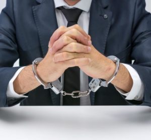 An accountant sits handcuffed after facing criminal charges. Texas accounting license defense attorneys can defend your license, and your livelihood.