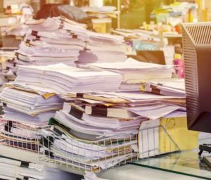 A huge stack of records sits on a desk. Poor record keeping is one reason a dentist may need the help of texas dental license defense attorneys.