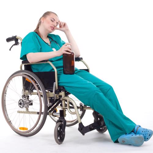A nurse is holding a bottle of alcohol, passed out in a wheel chair.