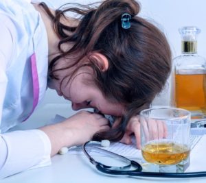 A female doctor falls asleep on her desk after drinking. Texas physician license defense attorneys often see doctors with chemical dependency issues.