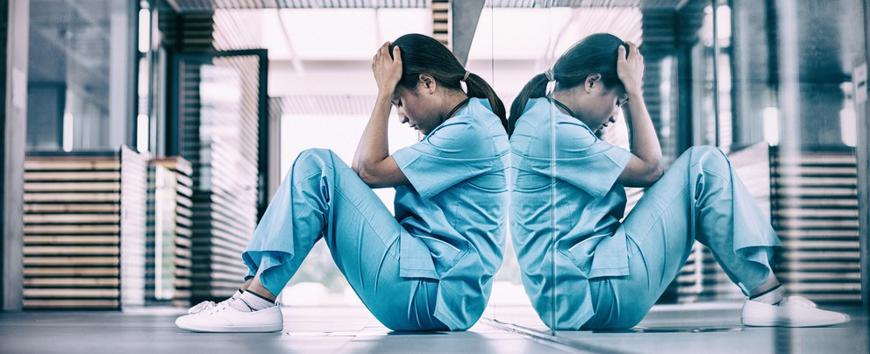 This image shows a nurse with her head in her hands.