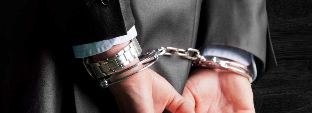 person handcuffed after being found guilty of a white collar crime